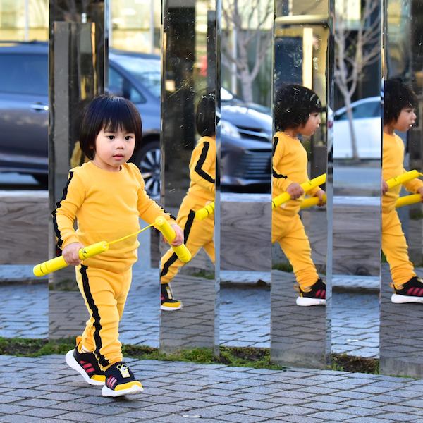 little boy in yellow track suit walking and reflected in mirrors